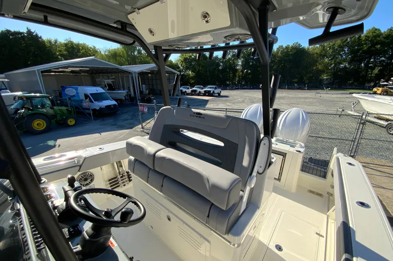 Slide: The Image of 2026 Cobia 305 Center Console boat interior with dual engines, parked near a warehouse. - 40