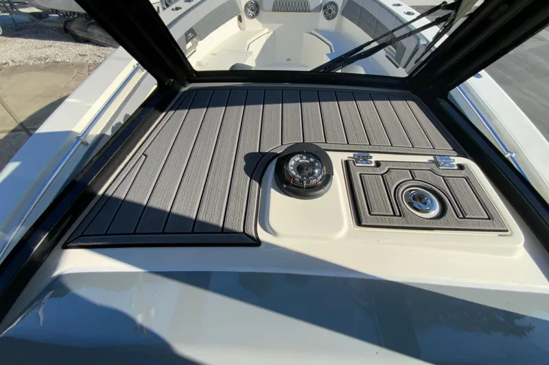 Slide: The Image of 2026 Cobia 305 Center Console boat dashboard with compass and storage compartment. - 47