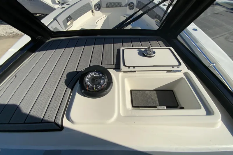 Slide: The Image of 2026 Cobia 305 Center Console boat dashboard with compass and storage compartments. - 48