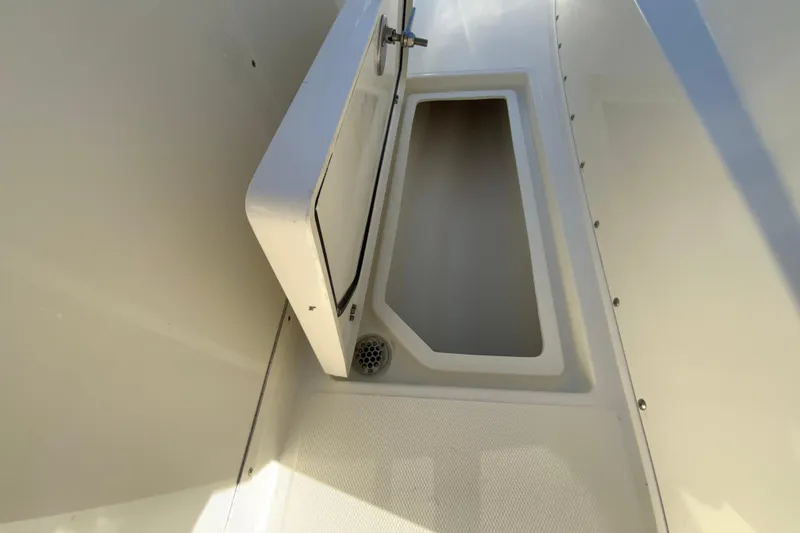 Slide: The Image of 2026 Cobia 305 Center Console storage compartment with open hatch and drain. - 59