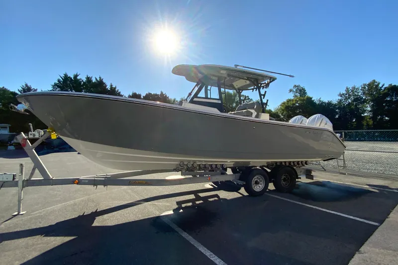 Slide: The Image of 2026 Cobia 305 Center Console boat on trailer under bright sun. - 6