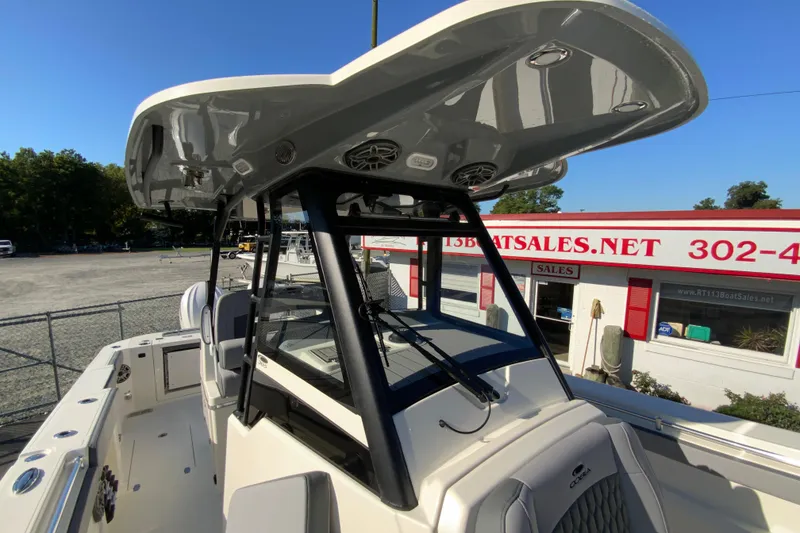 Slide: The Image of 2026 Cobia 305 Center Console boat at dealership, showcasing helm and T-top design. - 70