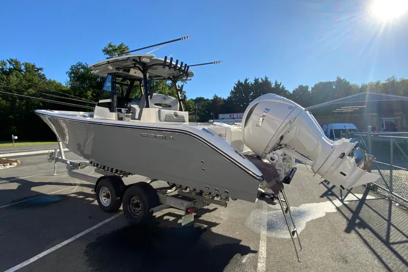 Slide: The Image of 2026 Cobia 305 Center Console boat on trailer, parked outdoors under clear sky. - 8