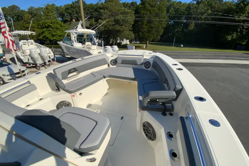 Slide: The Image of 2026 Cobia 305 Center Console boat interior with seating and speakers, parked outdoors. - 92