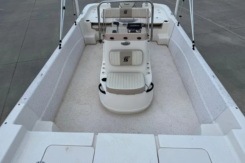 Slide: The Image of 2019 Carolina Skiff 218 DLV boat interior with seating and console, docked on concrete. - 8