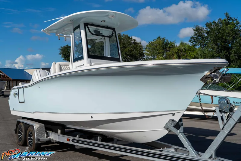 Slide: The Image of 2025 Sea Hunt Ultra 245 SE boat on trailer, under clear blue sky. - 35