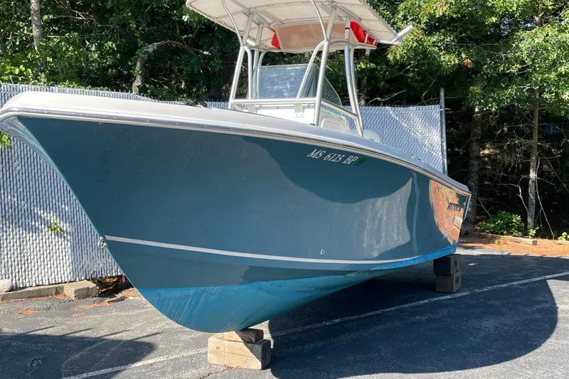 Slide: The Image of 2014 Sailfish 220 CC boat on blocks, parked outdoors with trees in the background. - 0