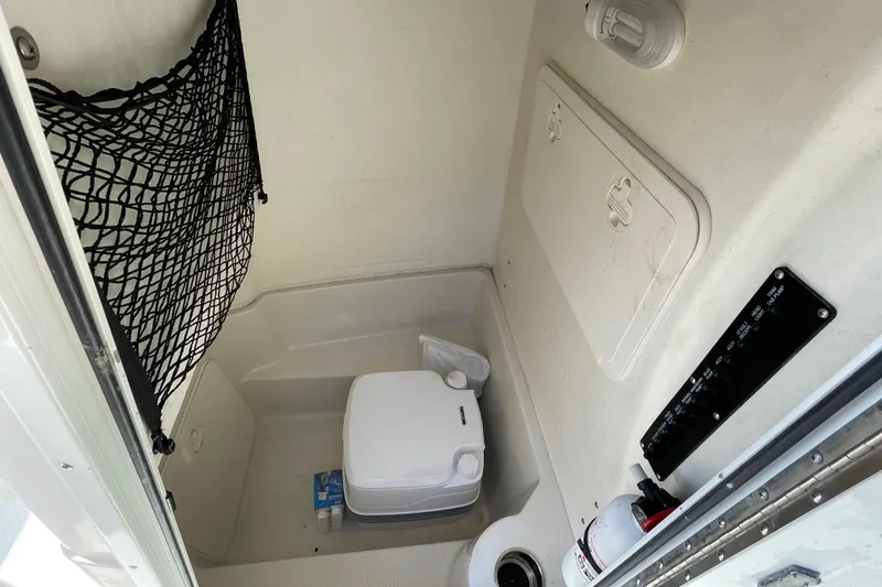 Slide: The Image of 2014 Sailfish 220 CC boat interior with portable toilet and storage net. - 14