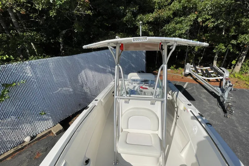 Slide: The Image of 2014 Sailfish 220 CC boat with T-top, parked on a trailer near a fence. - 15