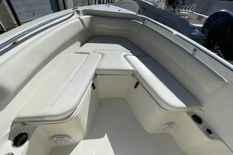 Slide: The Image of 2014 Sailfish 220 CC boat interior with white cushioned seating and cup holders. - 17