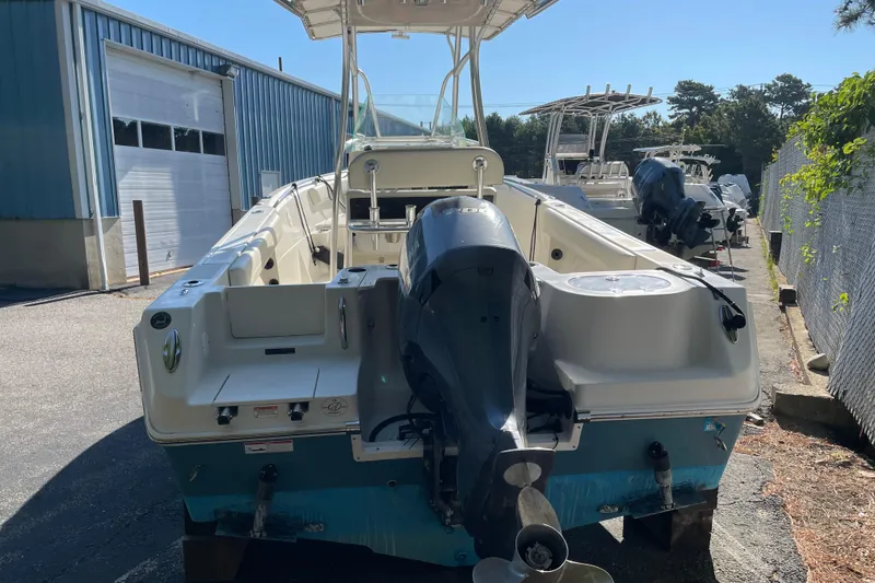 Slide: The Image of 2014 Sailfish 220 CC boat with outboard motor, parked near a blue building. - 18