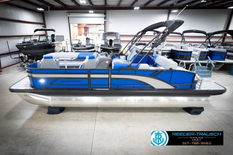 The Image of 2026 Bennington 22 SSB pontoon boat in showroom, featuring sleek blue design and modern seating. - 0