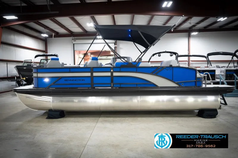 Slide: The Image of 2026 Bennington 22 SSB pontoon boat interior with blue and gray seating, cup holders, and logo. - 11