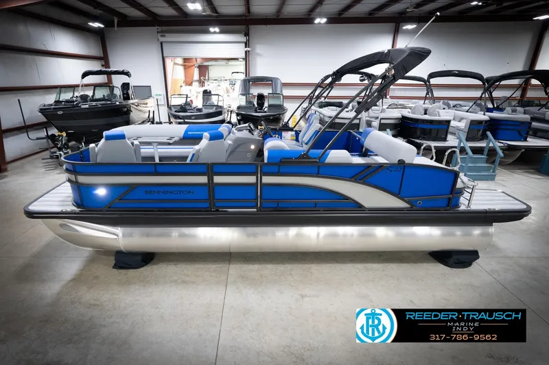 Slide: The Image of 2026 Bennington 22 SSB pontoon boat in a showroom, featuring sleek blue design. - 2