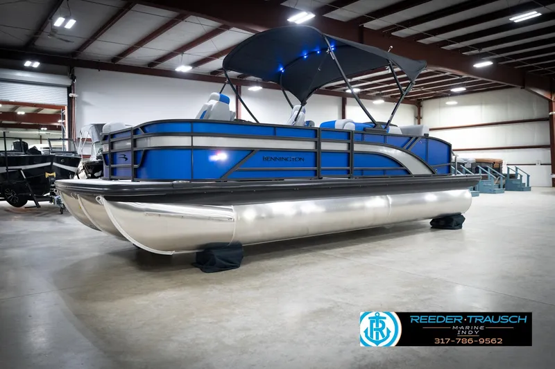 Slide: The Image of 2026 Bennington 22 SSB pontoon boat in showroom with blue accents and canopy. - 3