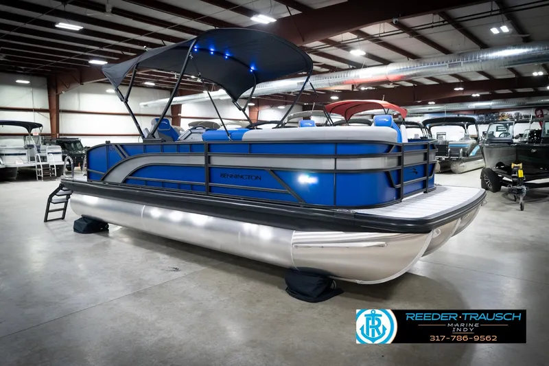 Slide: The Image of 2026 Bennington 22 SSB pontoon boat in showroom, featuring blue and silver design. - 6