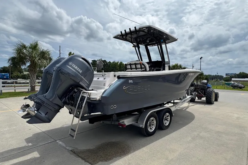 Slide: The Image of 2023 Robalo R250 Center Console boat on trailer with Yamaha engines, parked outdoors. - 2