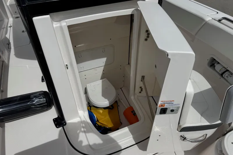 Slide: The Image of 2023 Robalo R250 Center Console boat interior with open storage compartment and marine toilet. - 6