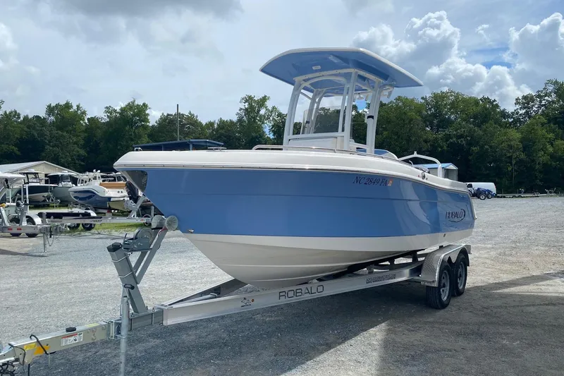 Slide: The Image of 2023 Robalo R222 Explorer boat on trailer, parked outdoors under cloudy sky. - 3