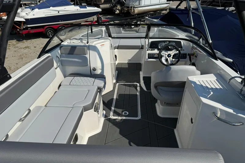 Slide: The Image of 2025 Bayliner D22I boat interior with modern seating and steering wheel, docked outdoors. - 10