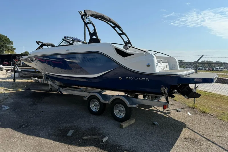 Slide: The Image of 2025 Bayliner D22I boat on trailer, blue and white design, parked outdoors. - 2