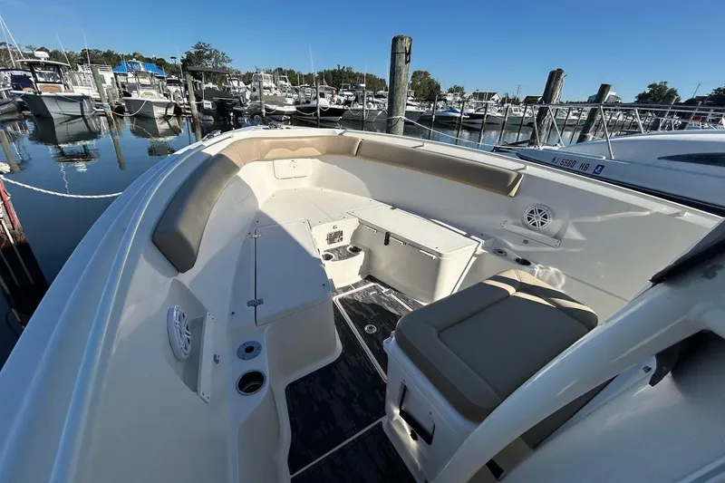Slide: The Image of 2019 Sailfish 270 CC boat interior at marina, featuring seating and storage. - 17