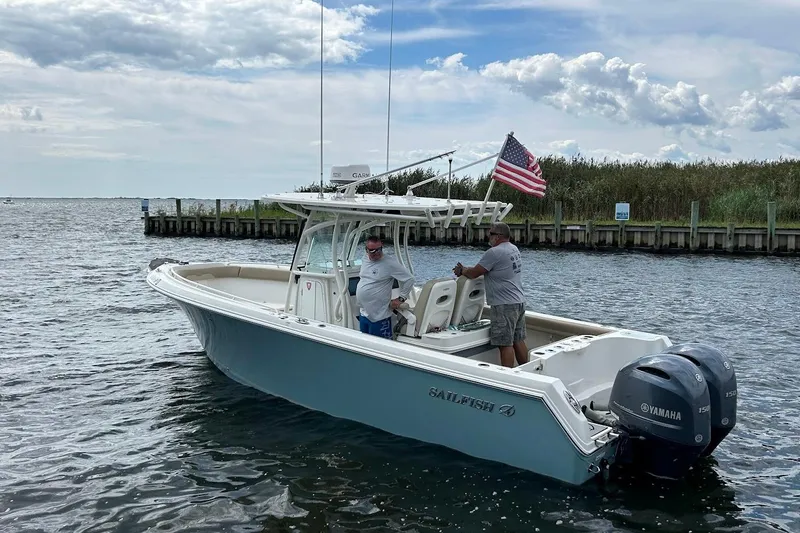 Slide: The Image of 2019 Sailfish 270 CC boat on water, American flag, Yamaha engines, two people onboard. - 3