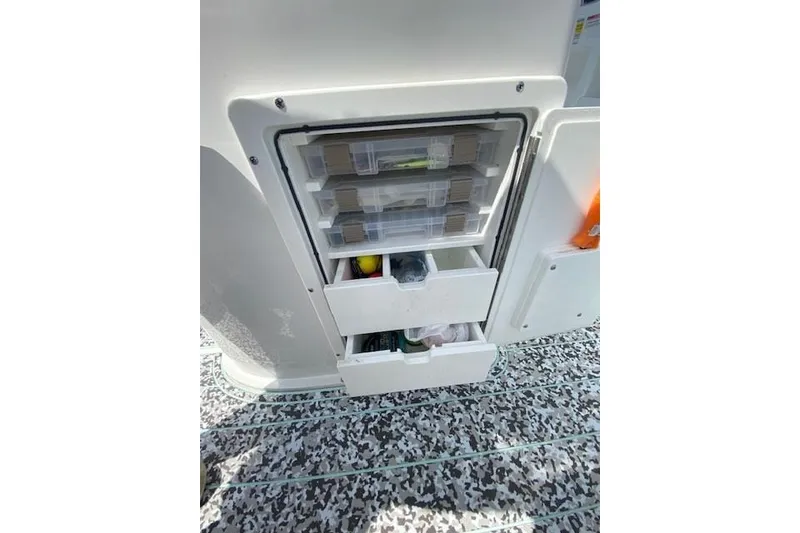 Slide: The Image of 2024 Sea Hunt BX 25 FS boat storage compartment with organized tackle boxes and drawers. - 29