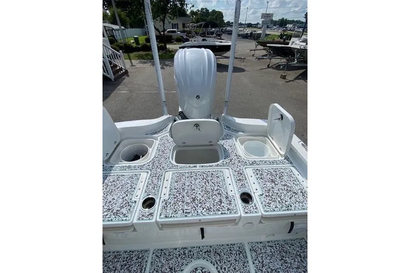 Slide: The Image of 2024 Sea Hunt BX 25 FS boat deck with storage compartments and motor, in a marina setting. - 8