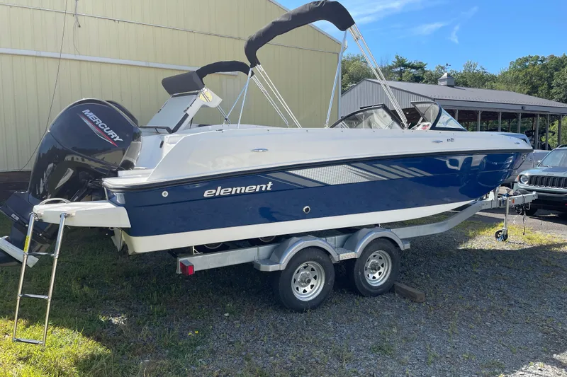 The Image of 2024 Bayliner Element E21 boat on trailer, featuring a Mercury outboard motor. - 1