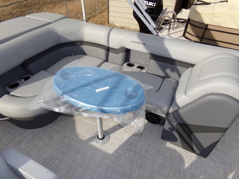 Slide: The Image of 2023 Trifecta 20C CS pontoon boat interior with gray seating and a blue table. - 20