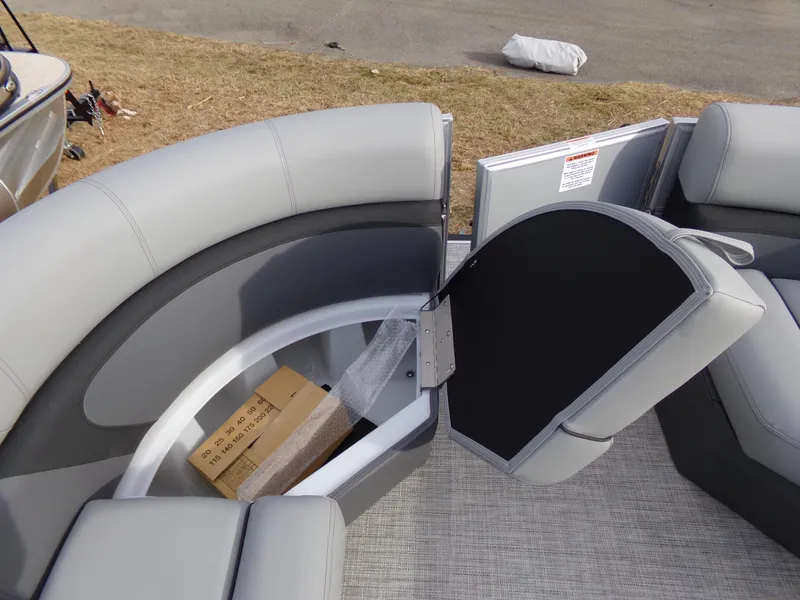 Slide: The Image of 2023 Trifecta 20C CS pontoon boat with open storage compartment and gray seating. - 9