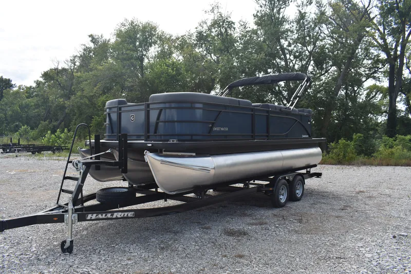 Slide: The Image of 2026 Godfrey Sweetwater 2086C Tritoon on trailer, parked outdoors with trees in background. - 6