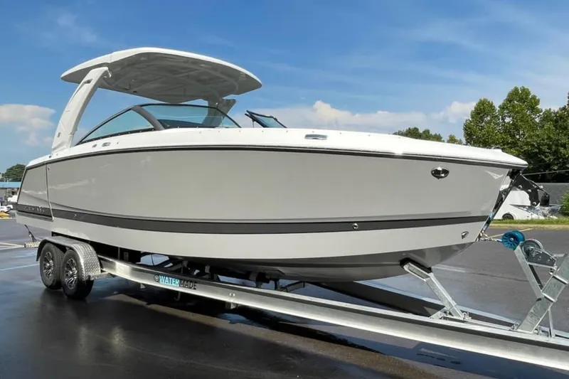 Slide: The Image of 2026 Four Winns H9 boat on trailer, sleek design, parked outdoors under blue sky. - 1