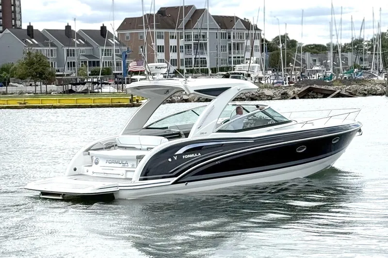 Slide: The Image of 2018 Formula 350 Sun Sport boat cruising near marina with waterfront buildings. - 2