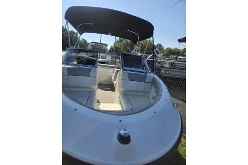 Slide: The Image of 2013 Bayliner 185 Bowrider with canopy, docked outdoors, showcasing spacious seating. - 4