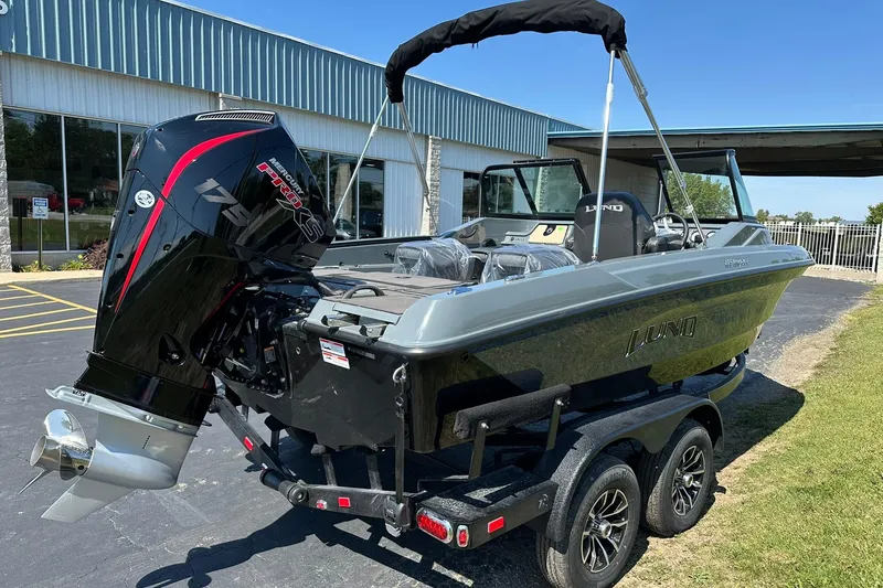 Slide: The Image of 2026 Lund 185 Impact GL boat with powerful outboard motor, parked outdoors. - 9