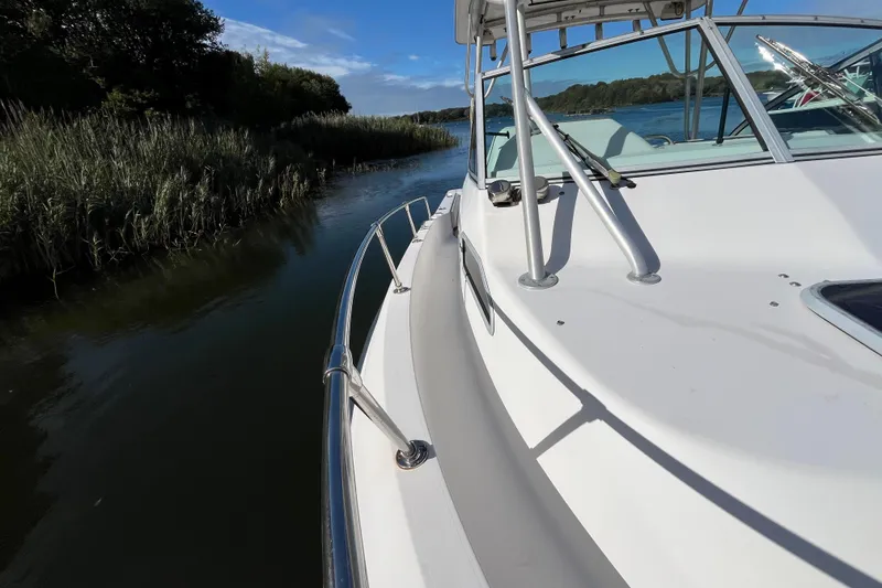Slide: The Image of 1999 Grady-White Gulfstream 232 boat navigating a narrow waterway with lush greenery. - 22