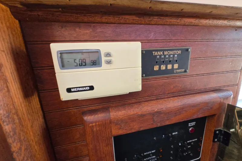 Slide: The Image of 1987 Silverton 34C boat interior with Mermaid thermostat and Raritan tank monitor on wooden panel. - 15