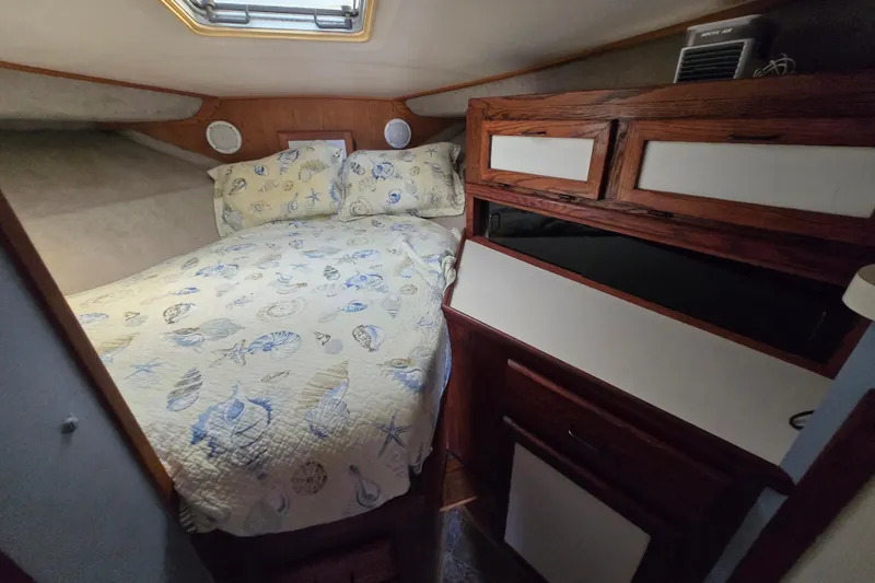 Slide: The Image of Cozy cabin interior of 1987 Silverton 34C with nautical-themed bedding and wooden storage. - 19
