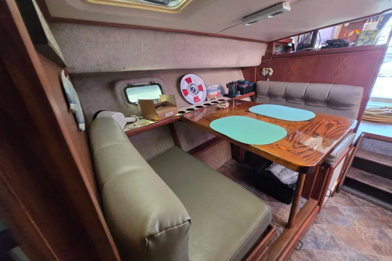 Slide: The Image of 1987 Silverton 34C cabin interior with dining area, wooden table, and cushioned seating. - 20