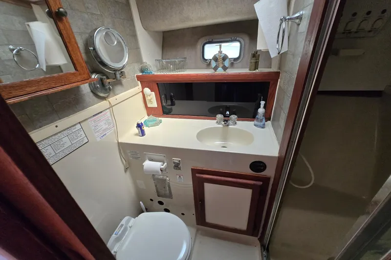 Slide: The Image of 1987 Silverton 34C yacht bathroom with sink, mirror, and shower area. - 23