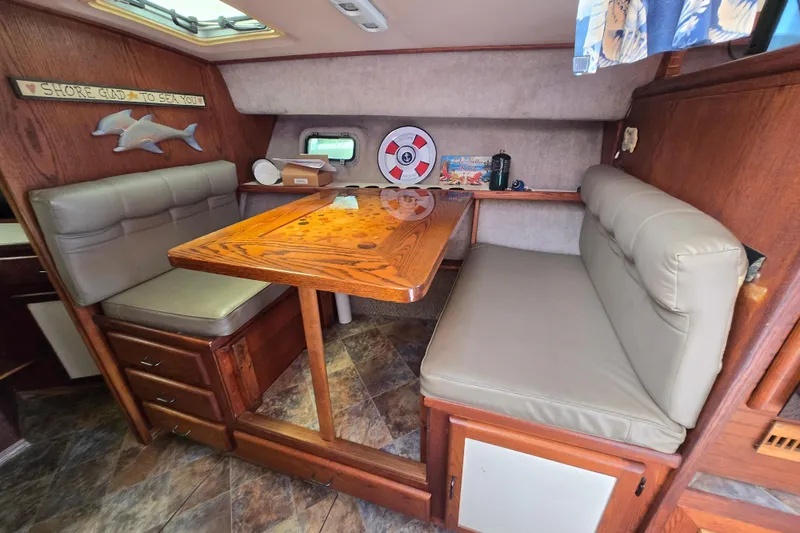 Slide: The Image of 1987 Silverton 34C cabin interior with wooden table, cushioned seating, and nautical decor. - 24