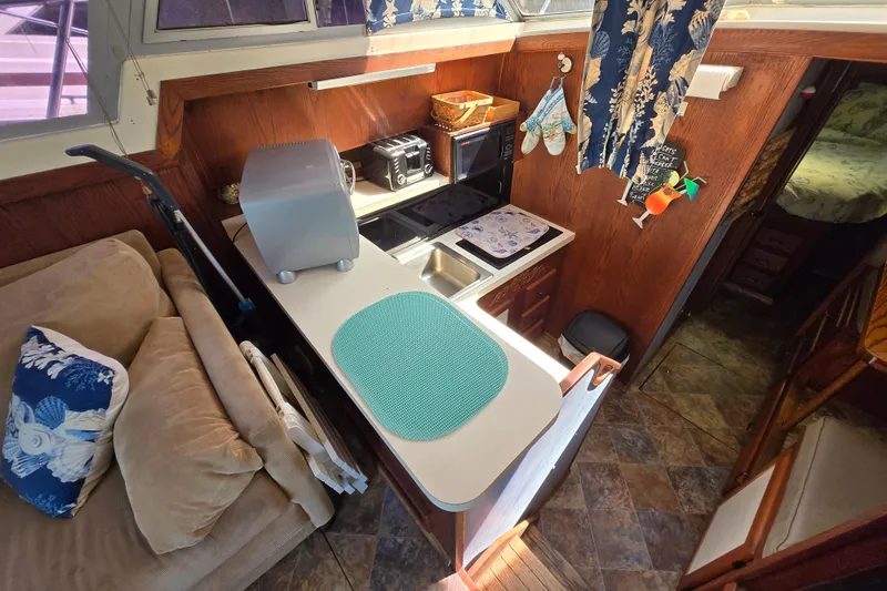Slide: The Image of 1987 Silverton 34C boat interior with cozy kitchen, wooden cabinetry, and nautical decor. - 6
