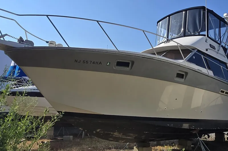 Slide: The Image of 1987 Silverton 34C boat on land, registration NJ 5574HA, with clear blue sky background. - 9