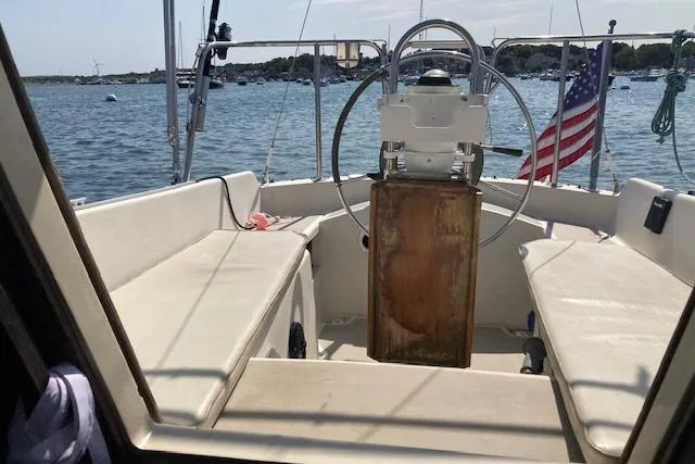 Slide: The Image of 1985 O'Day 28 sailboat cockpit with steering wheel, American flag, and scenic harbor view. - 18