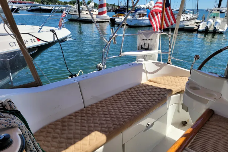 Slide: The Image of 1999 Beneteau Oceanis 351 sailboat cockpit with cushioned seating, docked in a marina. - 16