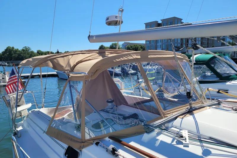 Slide: The Image of 1999 Beneteau Oceanis 351 sailboat docked, featuring tan canopy and American flag. - 2