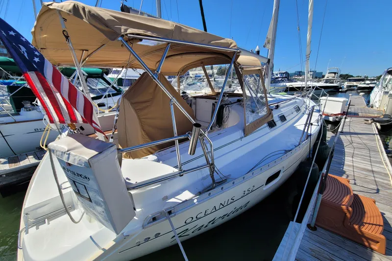Slide: The Image of 1999 Beneteau Oceanis 351 sailboat docked, featuring tan canopy and American flag. - 3