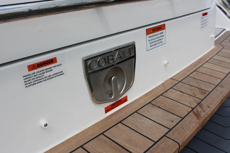 Slide: The Image of Cobalt R35 2025 boat stern with safety warnings and logo on wooden deck. - 17